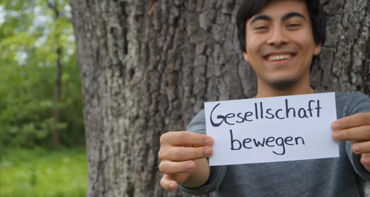 Teamer beim Team meX mit Schild „Gesellschaft bewegen“. Foto: Team meX