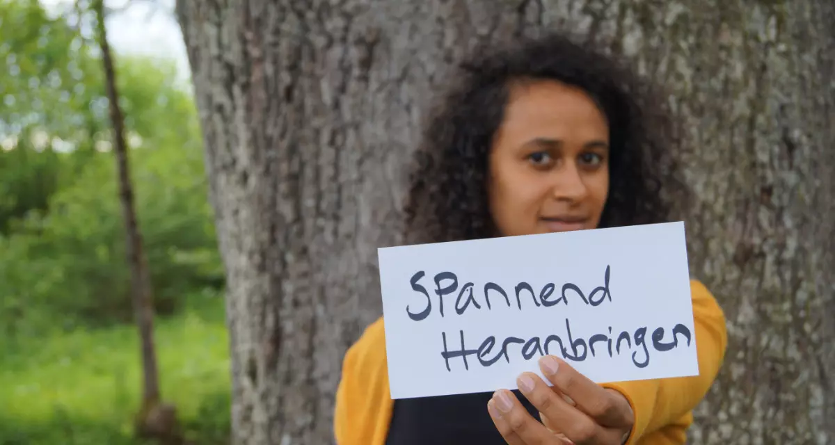 Teamerin beim Team meX mit Schild „Spannend heranbringen“. Foto: Team meX