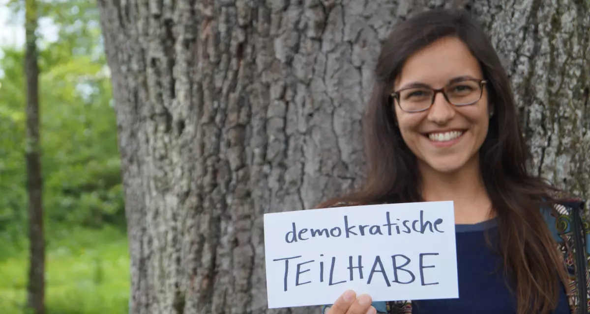 Teamerin beim Team meX mit Schild „Demokratische Teilhabe“. Foto: Team meX