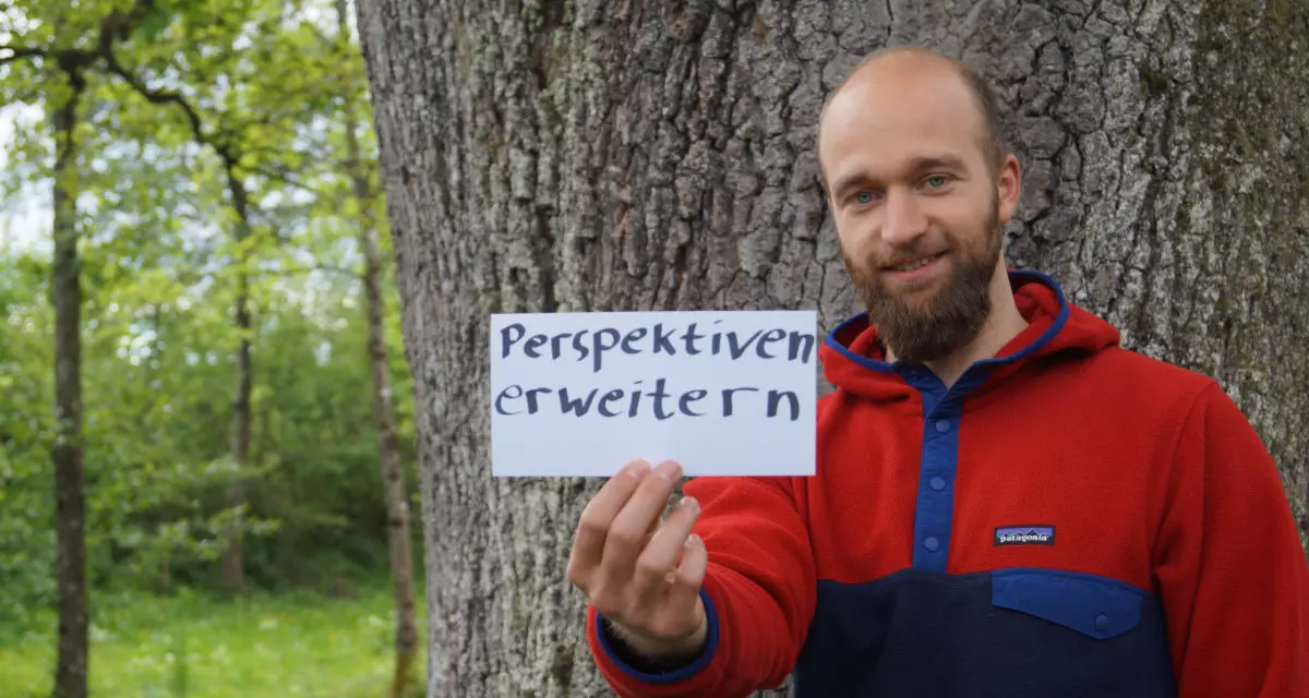Teamer beim Team meX mit Schild „Perspektiven erweitern“. Foto: Team meX
